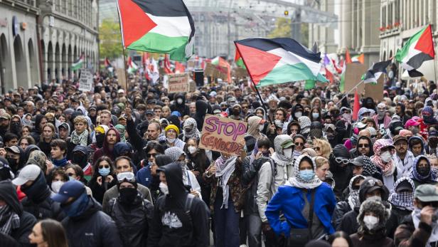 Viele Menschen demonstrieren mit palästinensischen Fahnen und Schildern, darunter eines mit der Aufschrift „Stop Genocide“.