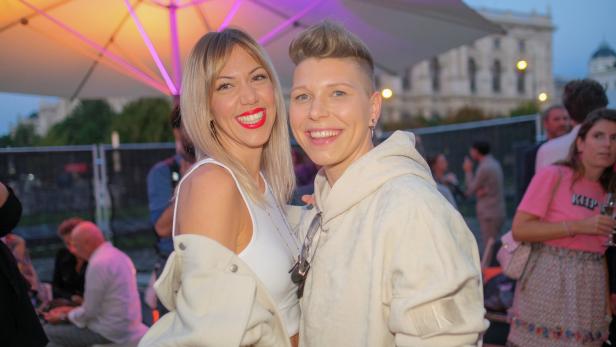 Zwei Frauen stehen eng beieinander und lachen in die Kamera