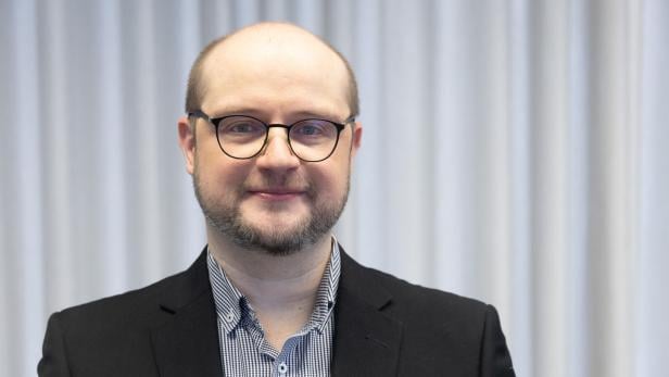 Dr. Ivan Milenkovic vor einem grauen Hintergrund.