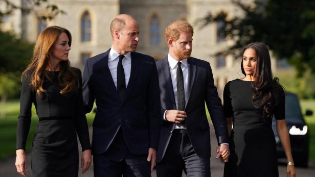 William, Kate, Harry und Meghan gehen zusammen, alle in Schwarz gekleidet.