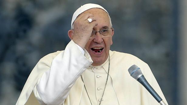 Papst Franziskus spricht an einem Mikrofon und hält seine Hand an die Stirn.