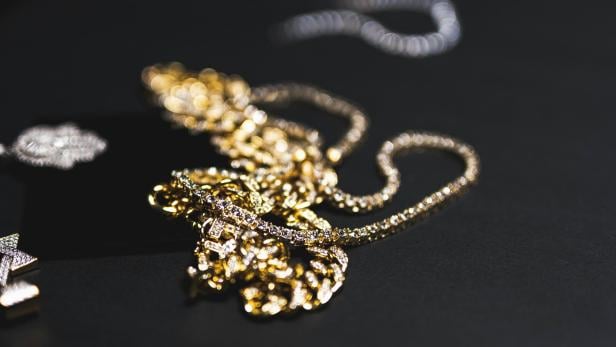 Goldschmuck liegt auf einem schwarzen Tisch