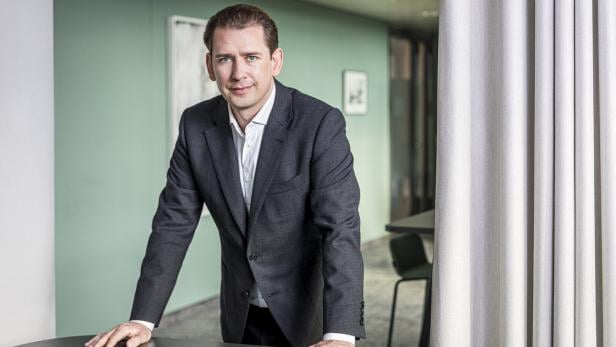 Sebastian Kurz im Anzug lehnt sich auf einen Tisch.