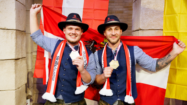 Zwei Männer halten die österreichische Flagge hoch. 