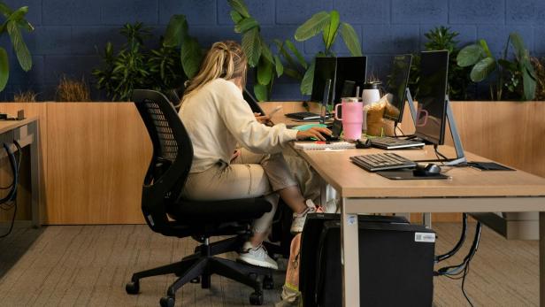 Frau sitzt auf schwarzem Bürostuhl am Arbeitsplatz