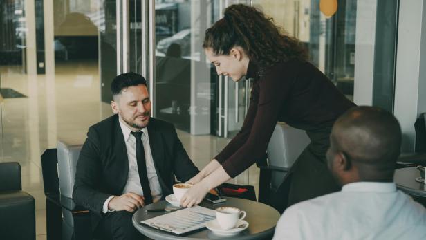 Kellnerinnen bestätigen: Dieser Trick führt zu deutlich mehr Trinkgeld. Trinkgeld: Frau bedient zwei Männer in einem Café