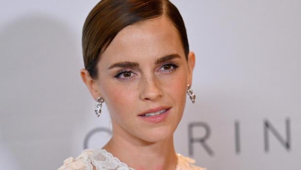 Emma Watson Emma Watson mit zurückgekämmtem Haar und Ohrringen vor hellem Hintergrund.