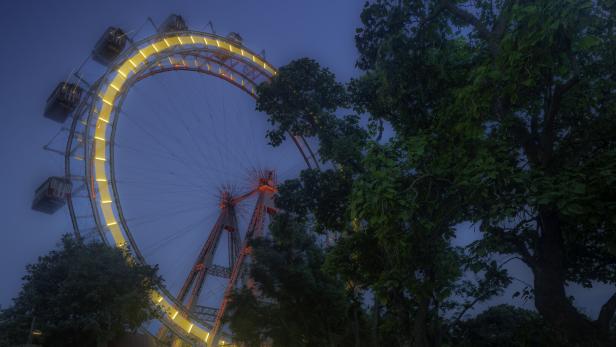 Das beleuchtete Wiener Riesenrad vor einem dunkelblaumen Himmel