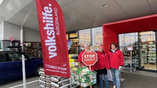 Volkshilfe, Sammlung von Lebensmitteln Drei Frauen der Volkshilfe Burgenland stehen vor einem Supermarkt mit einem "Stop Armut"-Schild.