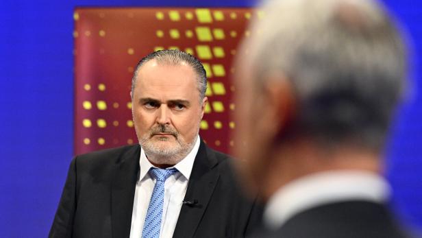 BURGENLAND-WAHL: ORF "ELEFANTENRUNDE" DER SPITZENKANDIDATEN Ein Mann mit Bart und Anzug blickt aufmerksam auf eine Person im Vordergrund.