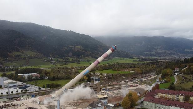 ++ HANDOUT ++ STEIERMARK: RHI-SCHORNSTEIN "LANGER ERNST" IN TRIEBEN GESPRENGT Ein hoher Schornstein stürzt kontrolliert um und wirbelt dabei Staub auf, im Hintergrund grüne Felder und Berge.