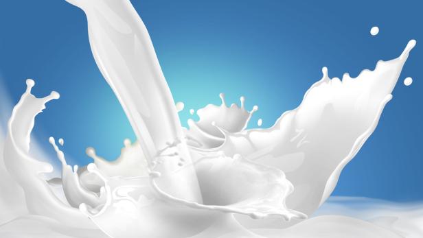 Ein Schwall Milch spritzt vor einem hellblauen Hintergrund.