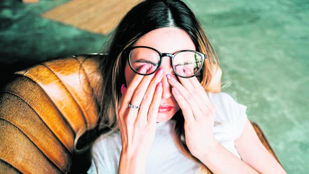 Young woman rubs her eyes after using glasses. Eye pain or fatigue concept.