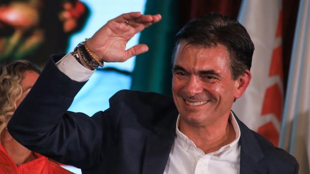 Rodrigo Paz Pereira elected as new President in Bolivia Ein Mann im Anzug lächelt und hebt die Hand zum Gruß, im Hintergrund sind Fahnen zu sehen.