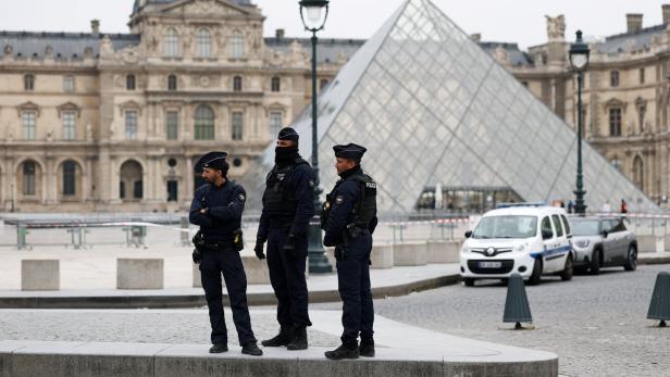 Police stand near the pyramid of the Louvre museum after reports of a robbery, in Paris Police stand near the pyramid of the Louvre museum after reports of a robbery, in Paris