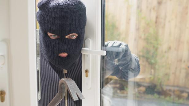 Eine maskierte Person mit Brecheisen versucht, eine Terrassentür aufzubrechen.