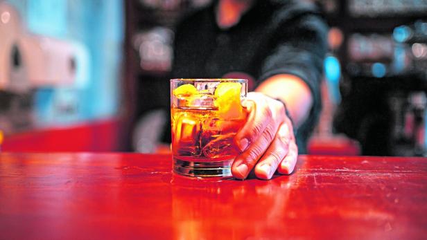 Bartender serving a cocktail drink on a bar counter Jemand greift nach einem Glas Alkohol.