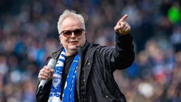 Herbert Grönemeyer Herbert Grönemeyer mit Sonnenbrille, Schal des VfL Bochum und Mikrofon zeigt in die Ferne.