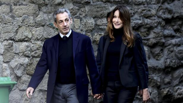 Nicolas Sarkozy und Carla Bruni Nicolas Sarkozy und Carla Bruni gehen händchenhaltend vor einer Steinmauer entlang.