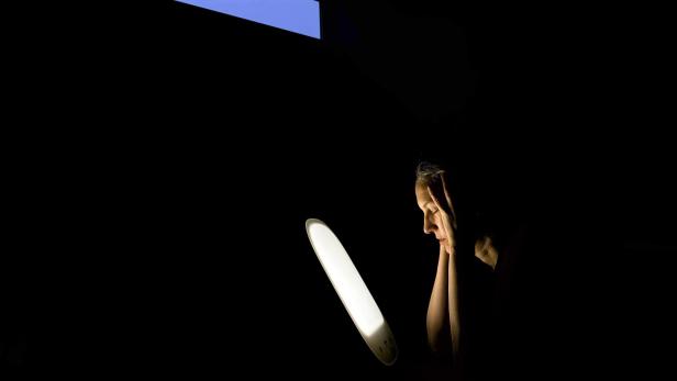 Frau im Dunkeln vor Tischlampe