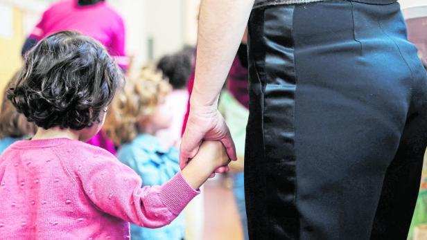 School starts in France after summer break Kindergarten Symbolbild: Eine Frau hält die Hand eines kleinen Kindes