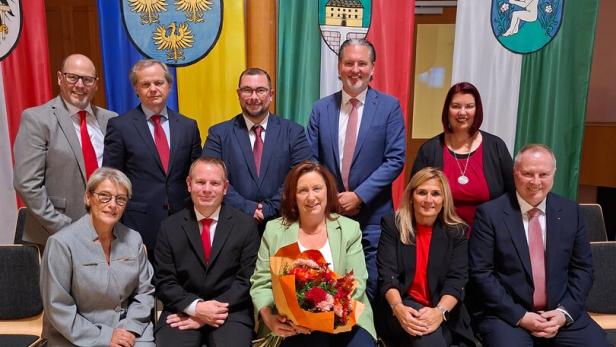 Mehrere Personen sitzen und stehen vor Flaggen