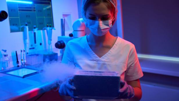 Eine Frau hält ein Gefäß mit flüssigem Stickstoff in der Hand.