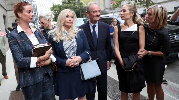 Virginia Giuffre Eine Gruppe von formell gekleideten Personen, darunter Virginia Giuffre, steht im Freien vor einem Gebäude.