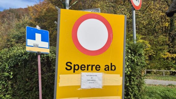 46-219673063 Straßensperre mit Hinweisschild „Sperre ab“, umgeben von weiteren Verkehrszeichen und herbstlicher Vegetation.