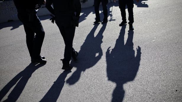 Polizeibeamte stehen auf einer Straße, ihre Schatten sind lang und deutlich sichtbar.