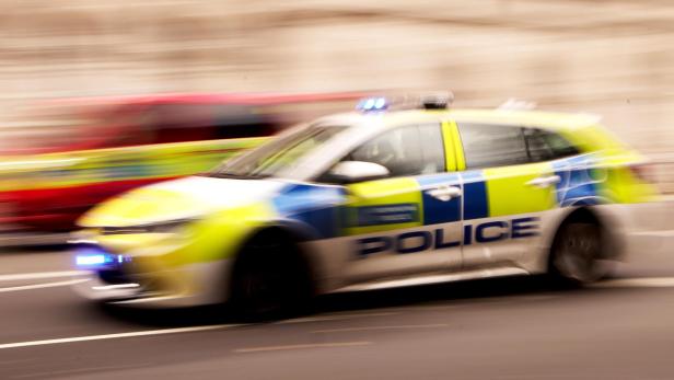 Ein Polizeiwagen fährt mit Blaulicht schnell auf der Straße.
