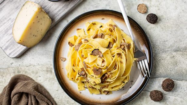 Top view of truffle fettuccine with mushrooms, long egg pasta. Italian first course made with hard cheese and butter. Ingredients.
