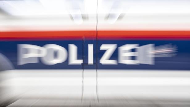 Verwischte Aufnahme eines Polizeiautos mit der Aufschrift "POLIZEI" in Weiß auf blauem Grund.