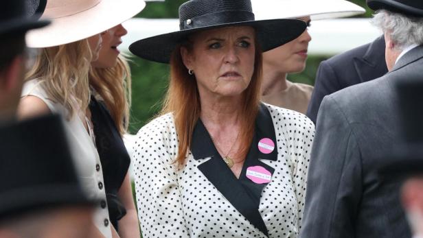 Sarah Ferguson Sarah Ferguson, in einem gepunkteten Kleid und Hut, steht inmitten einer Menschenmenge mit Hüten und Anzügen.