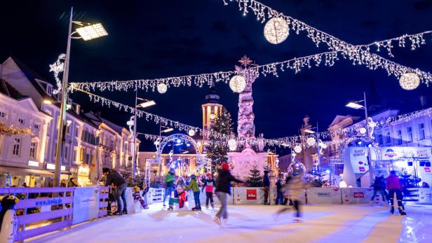 Die Aufnahme zeigt den weihnachtlich dekorierten Rathausplatz inklusive Eislauffläche in der Nacht.