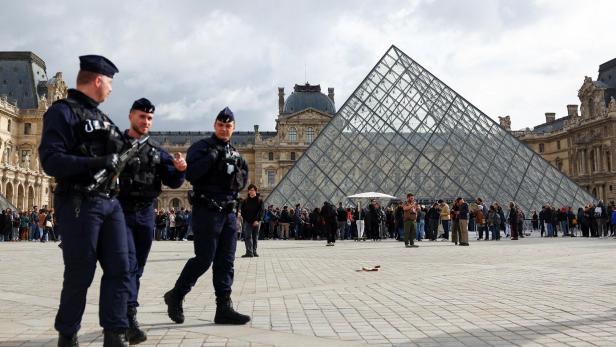 Bewaffnete Polizisten patrouillieren vor der Glaspyramide des Louvre in Paris.