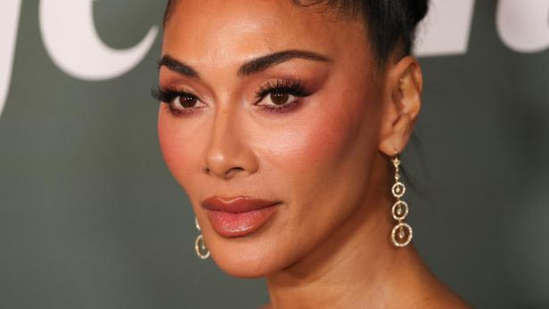 Nicole Scherzinger mit elegantem Make-up, hochgestecktem Haar und goldenen Ohrringen blickt ernst nach vorn.