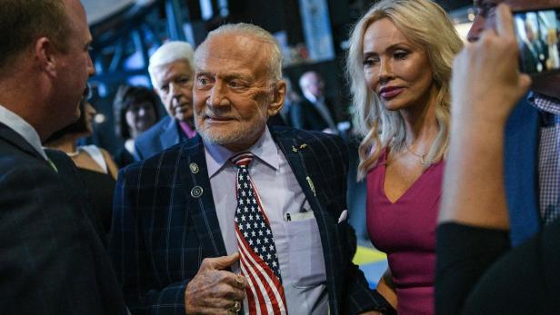 Buzz Aldrin  Buzz Aldrin mit Krawatte in US-Flaggen-Optik wird von seiner blonden Frau begleitet.