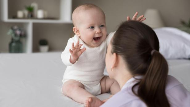 Ganzheitliche Baby-Balancing-Ausbildung von Iris Lichtenberger an der HOLFINITY Akademie stärkt Babys mit Kinesiologie und Cranio Sacral Techniken. Ein Baby greift nach seiner Mutter, mit offenem Mund. // Ganzheitliche Baby-Balancing-Ausbildung von Iris Lichtenberger an der HOLFINITY Akademie stärkt Babys mit Kinesiologie und Cranio Sacral Techniken.