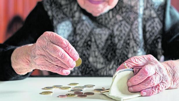 Elderly woman sitting at the table counting money in her wallet. Altersvorsorge