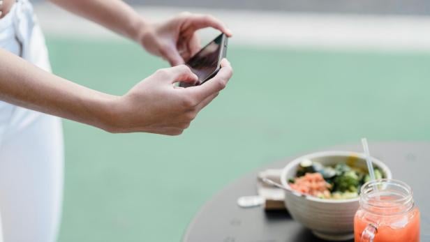 Eine Person macht ihrem Smartphone ein Foto von einer Mahlzeit