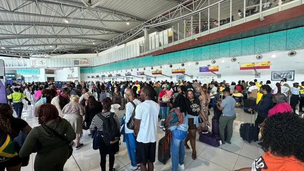 Viele Menschen stehen mit Gepäck in langen Schlangen an den Check-in-Schaltern eines Flughafens.