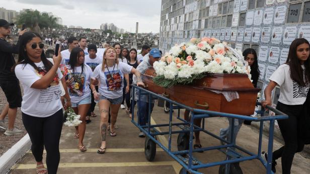 Funeral for Ravel Rios, one of those killed during a deadly police operation against drug trafficking, in Rio de Janeiro Mehrere trauernde Menschen begleiten einen mit Blumen geschmückten Sarg auf einem Friedhofswagen durch eine Grabstätte.