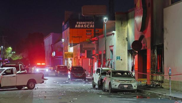 Fire in a store in northwestern Mexico kills multiple people in Hermosillo Mehrere beschädigte Autos stehen nachts auf einer von Polizei und Feuerwehr beleuchteten Straße mit Spuren von Zerstörung.