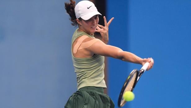 Lilli Tagger schlägt einen Ball mit dem Schläger, ihr Arm ist mit Tape bandagiert.