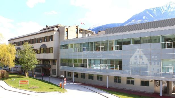 Spitalgebäude von außen, im Hintergrund Berge