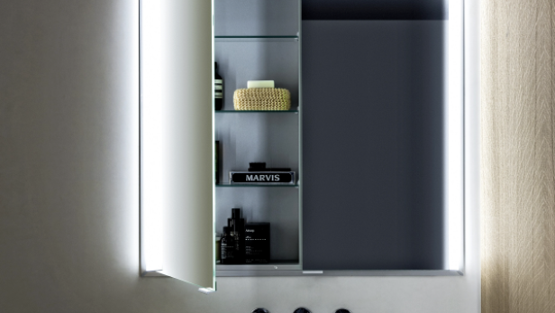 Moderner Badezimmerspiegel mit geöffneter beleuchteter Tür, weißes Waschbecken, Seifenspender und graue Wand.