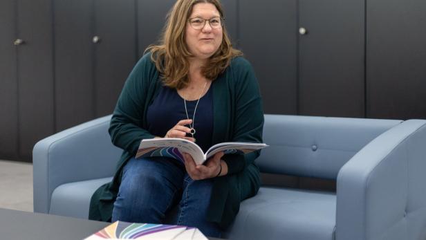 Margreth Keiler sitzt auf einer Couch mit aufgeschlagenem Bericht