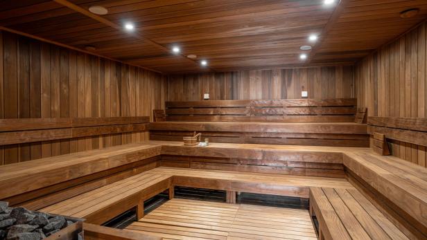 Eine Sauna mit Holzvertäfelung, Bänken und einem Ofen mit Steinen.