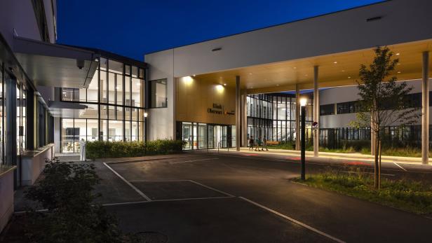 Die Klinik Oberwart präsentiert sich bei Dämmerung mit moderner Architektur und beleuchteten Fenstern.